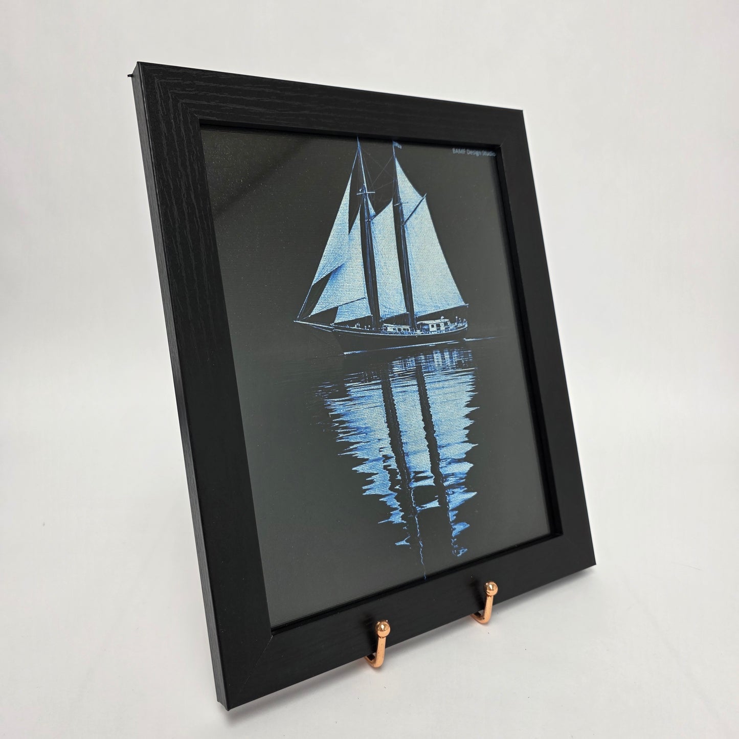 Black framed canvas of sailboat with reflection on water. Black and blue accents.
