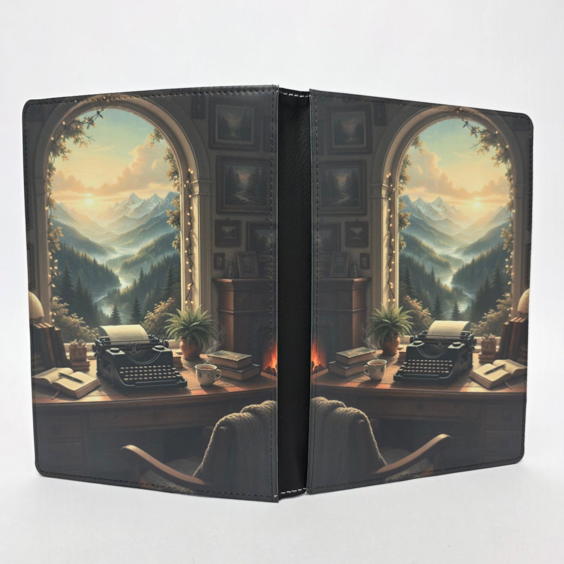 Journal cover with a typewriter sitting on a desk in front of a scenic window overlooking mountains.