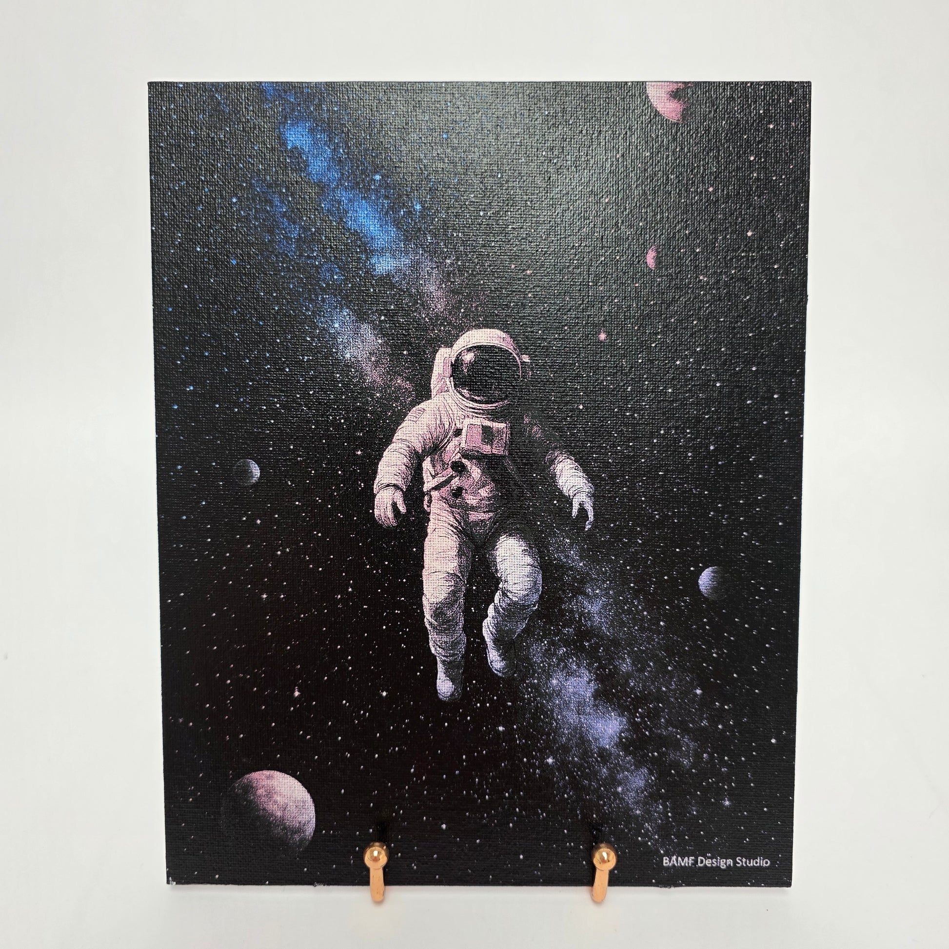 Canvas print of an astronaut floating in space surrounded by stars and planets. Black, blue, and purple accents.