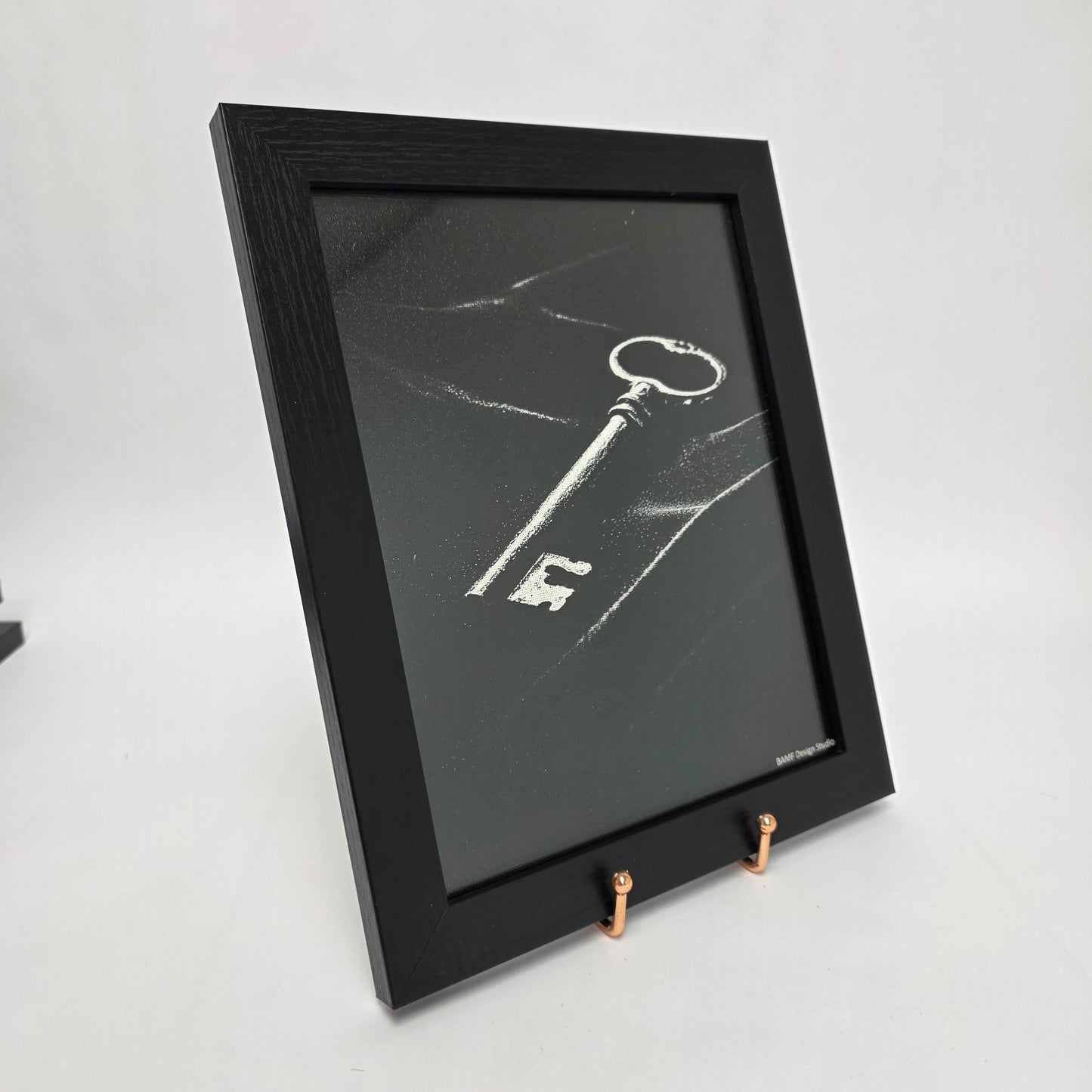 Black framed canvas print of a vintage key. Black and white accents.