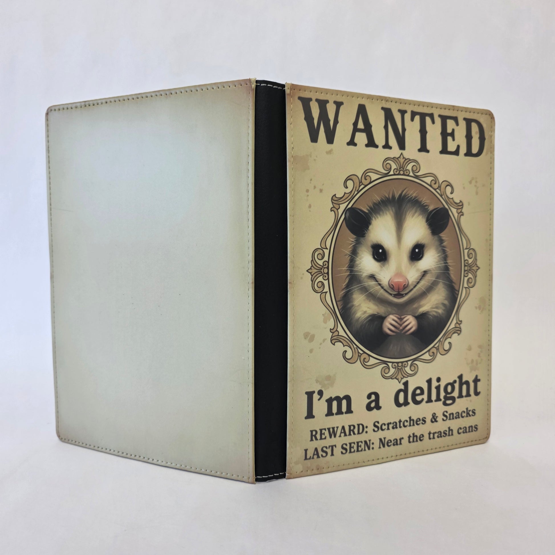 Notebook cover with an opossum illustration and 'Wanted' text on a beige background. The back of the cover is a solid beige color.