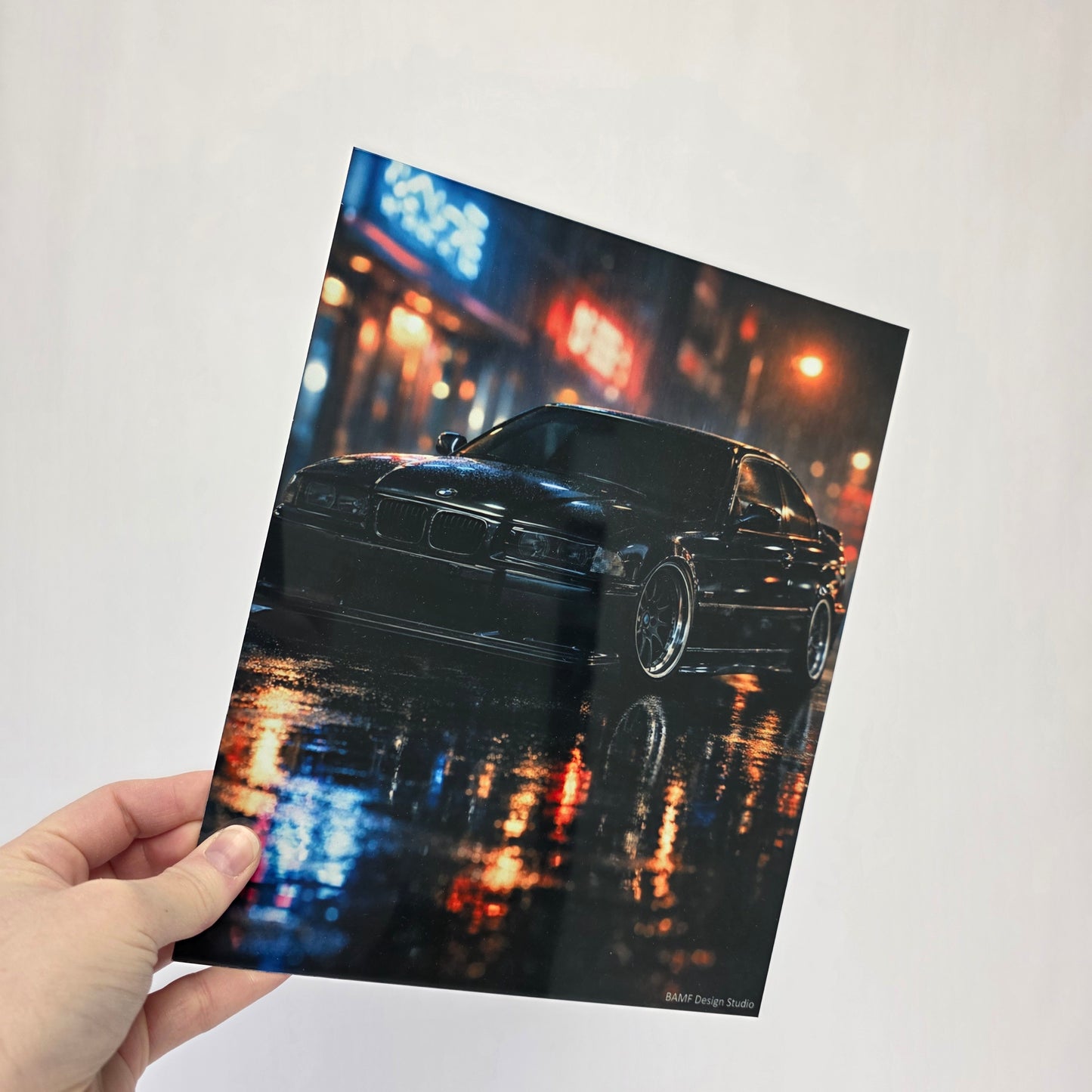 Hand holding a photo of a car at night with colorful lights.