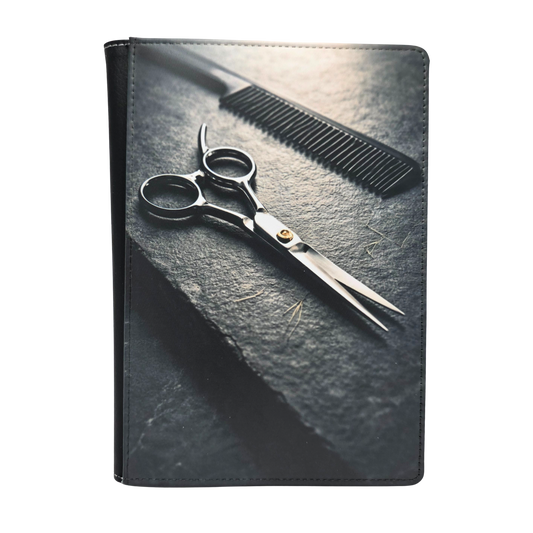 Scissors and comb on a textured slate surface. Grayscale color.