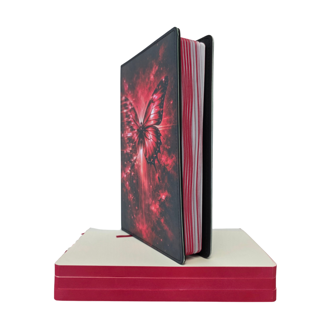 Notebook with butterfly design on cover on a white background, sitting on top of a stack of red paper.